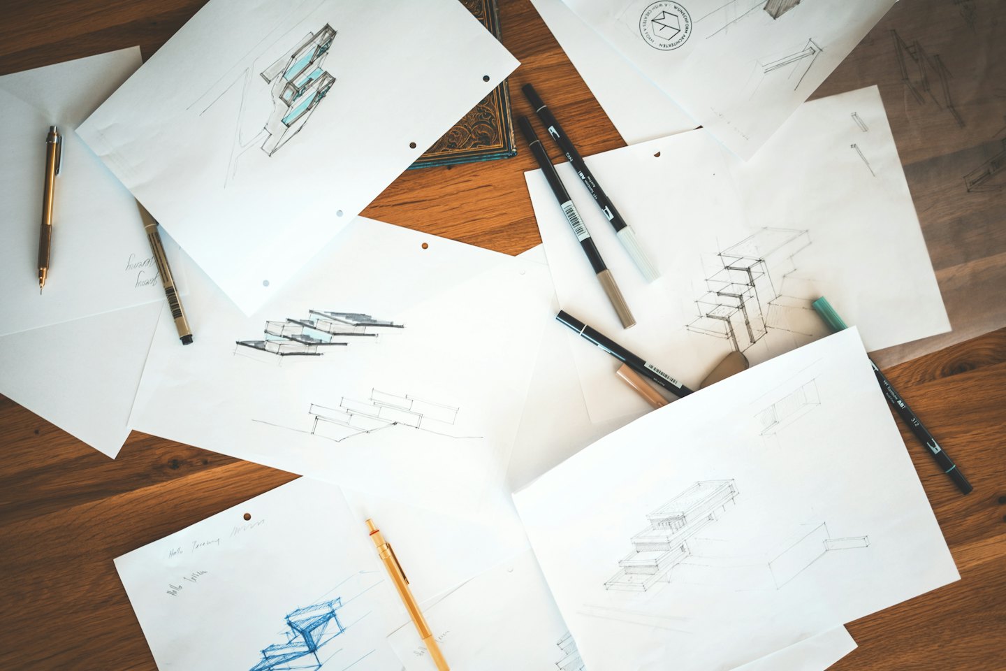 Architectural sketches and pens on a wooden table.