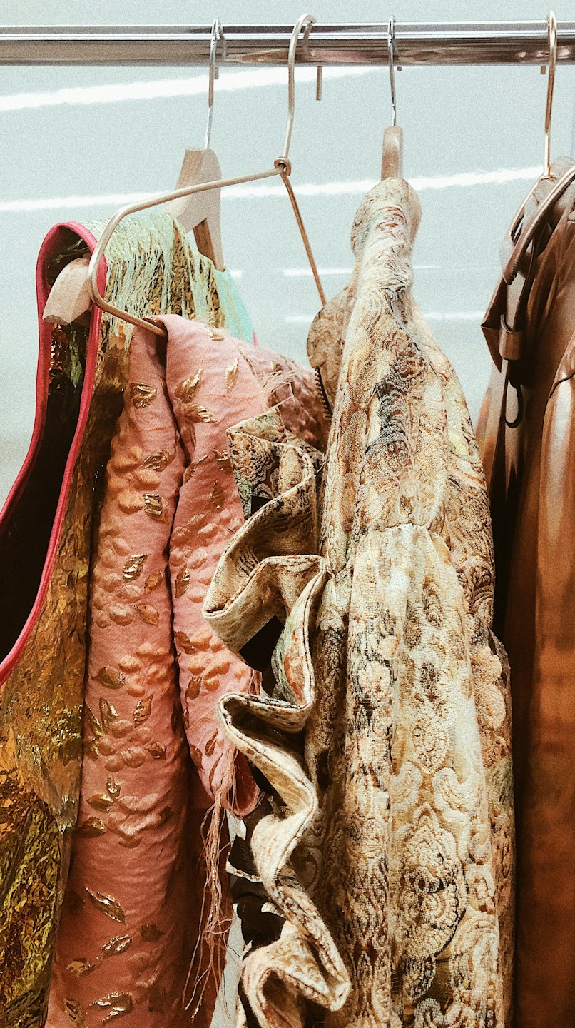 Ornate gold and pink garments hanging on a clothing rack.