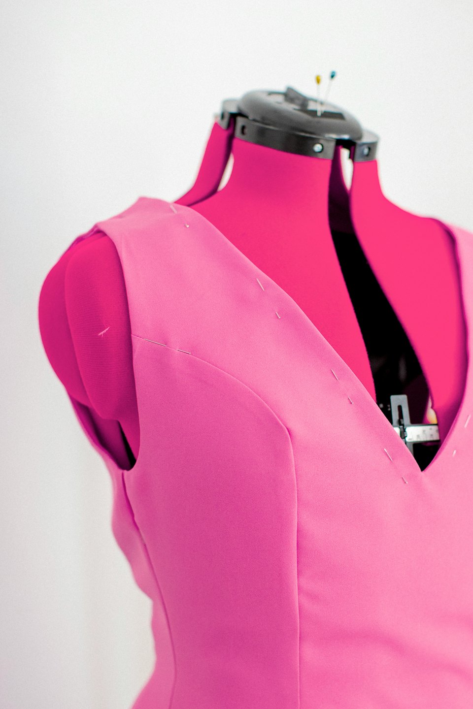 Pink garment pinned to dress form during tailoring.